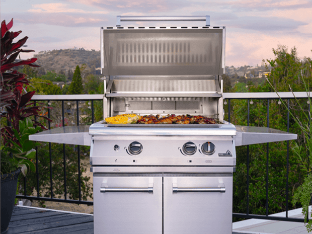 gas grill on a patio with a view, food cooking on grill with sunset behind